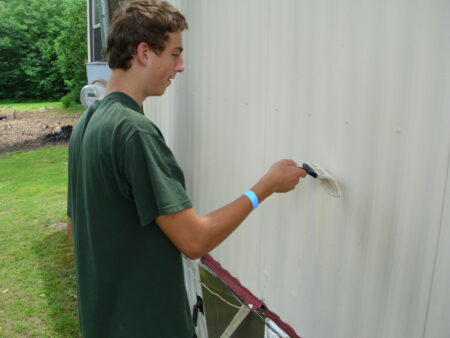 Participant painting exterior of mobile home